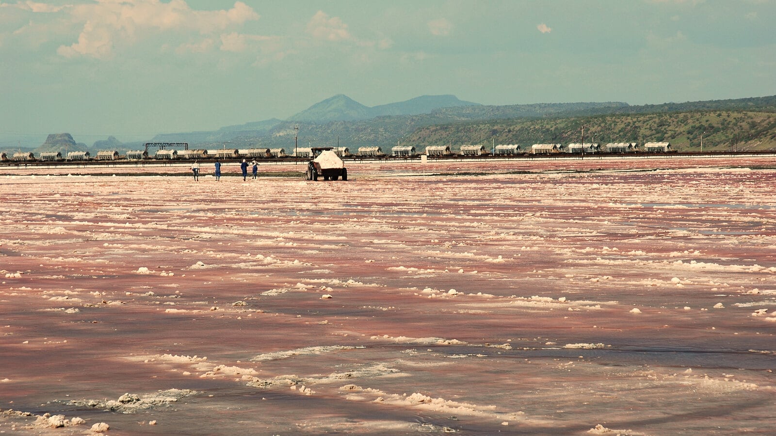Soda crust on Lake Magadi with workers and the soda works train in the distance